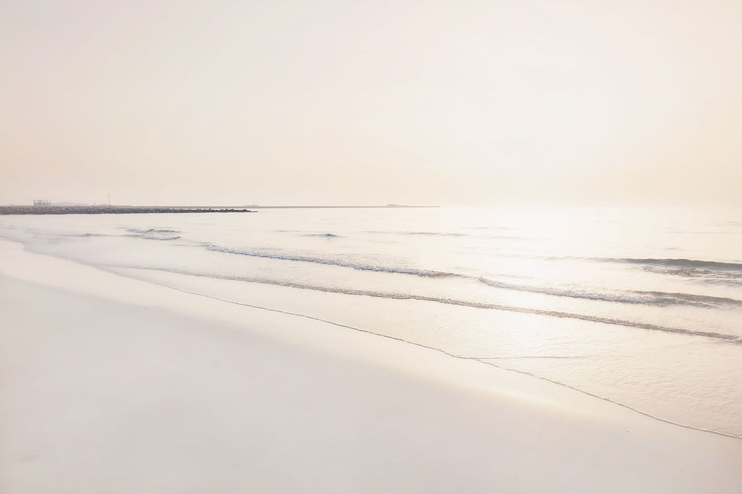 Minimalist beach scene with soft waves rolling onto shore in muted pastel tones.