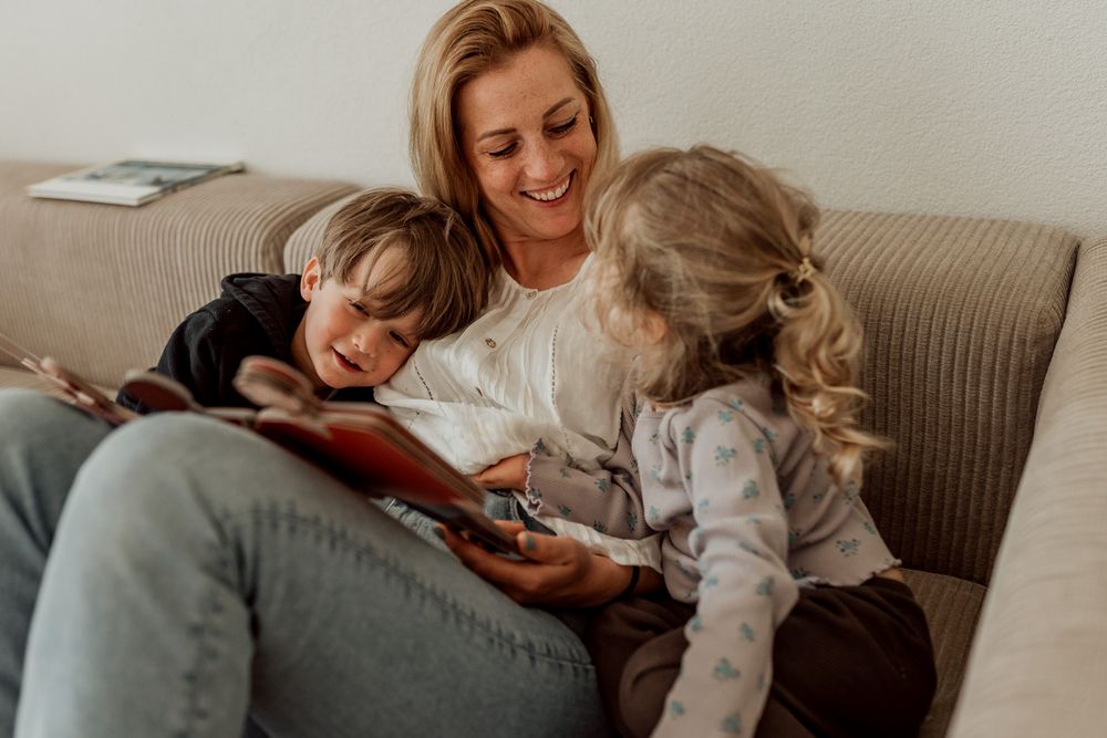 Herzerwärmendes Foto von einer Mutter, die mit ihren Kindern ein Buch anschaut.