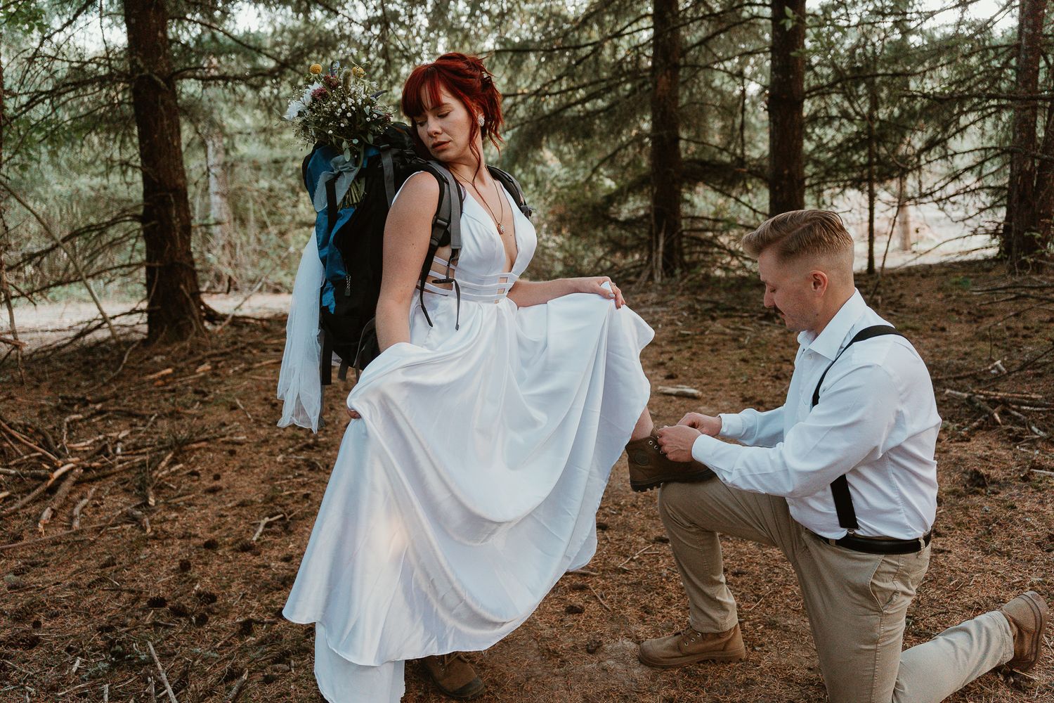 Groom ties the bride's shoes for the hike. Editorial feel.