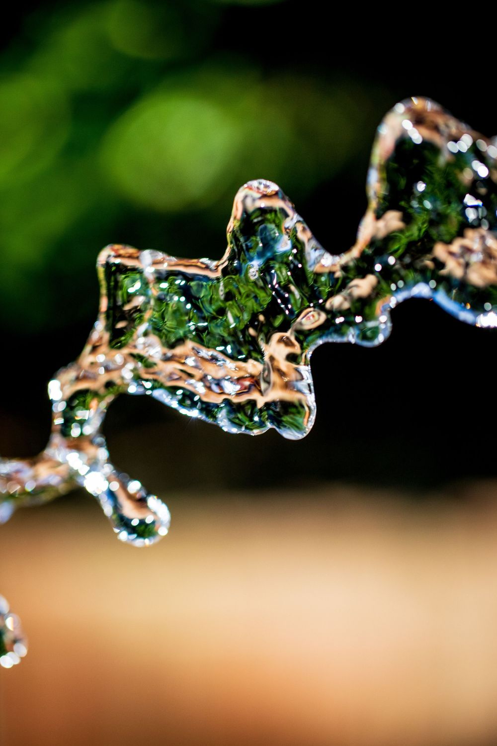 Macro shot of water coming out of a hose shot at high speed with a green bokeh background.