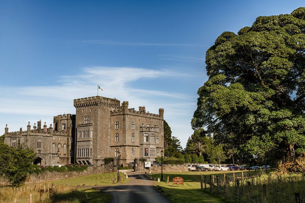 Historic castle with stone facade and turrets set against blue sky and green landscape at a Sligo.
