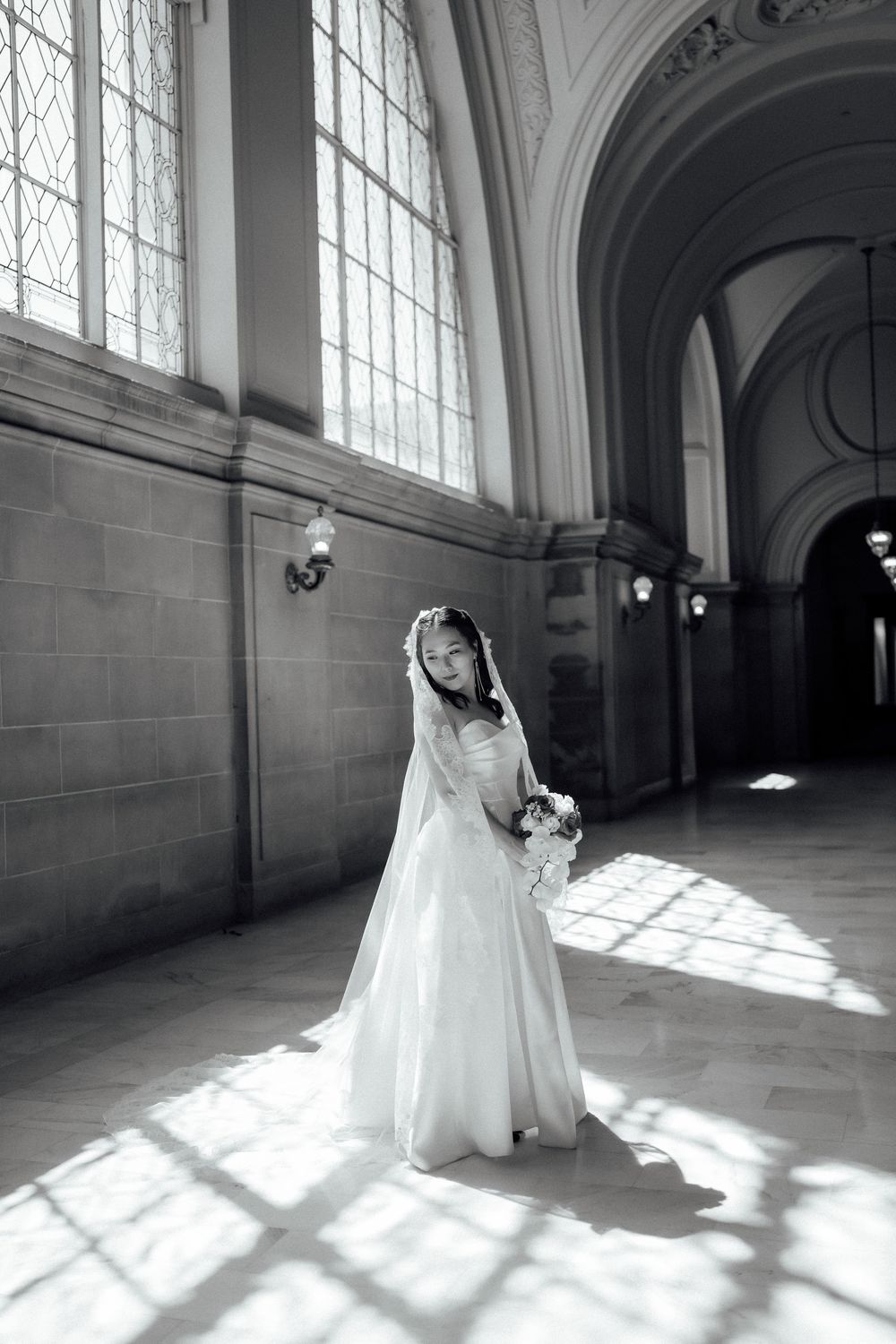 Black and white photo series of a bride dancing in natural window light within a classical architectural space.