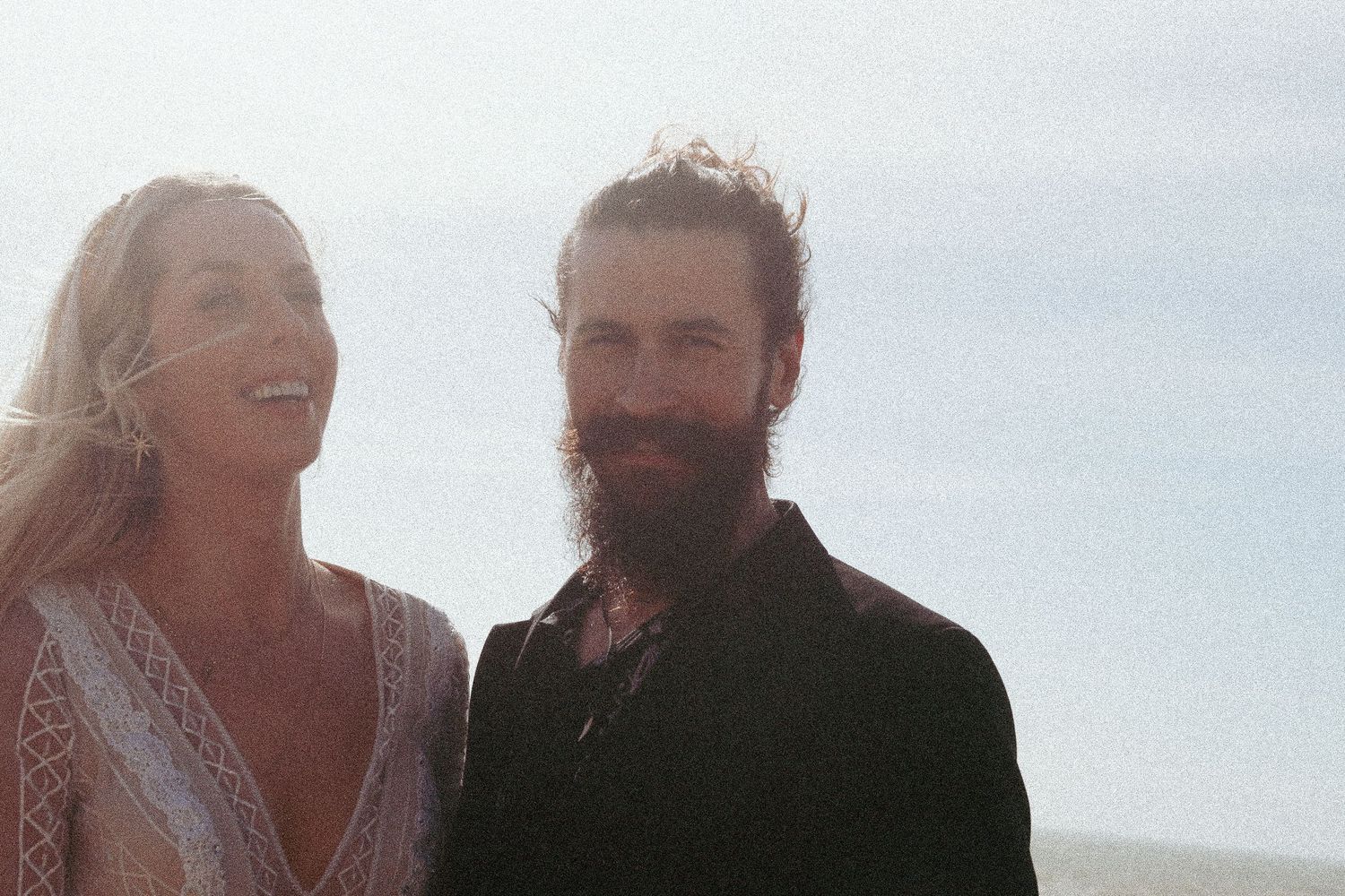 Bride and groom laughing in the afternoon sunlight on Brighton beach by Dominique Lauren Photography