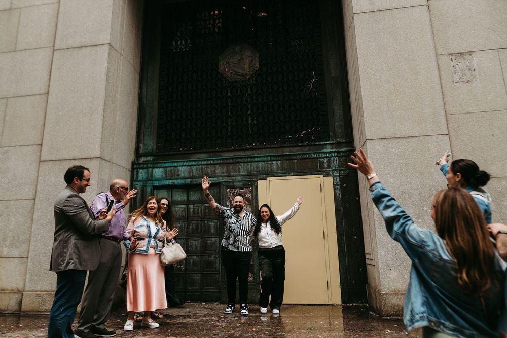People posing playfully against a wall outside a historic building with decorative stonework.