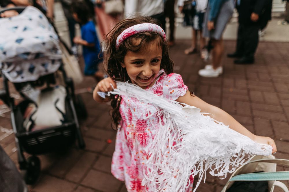 Children play with silly string during a festive outdoor celebration on a brick paved area.