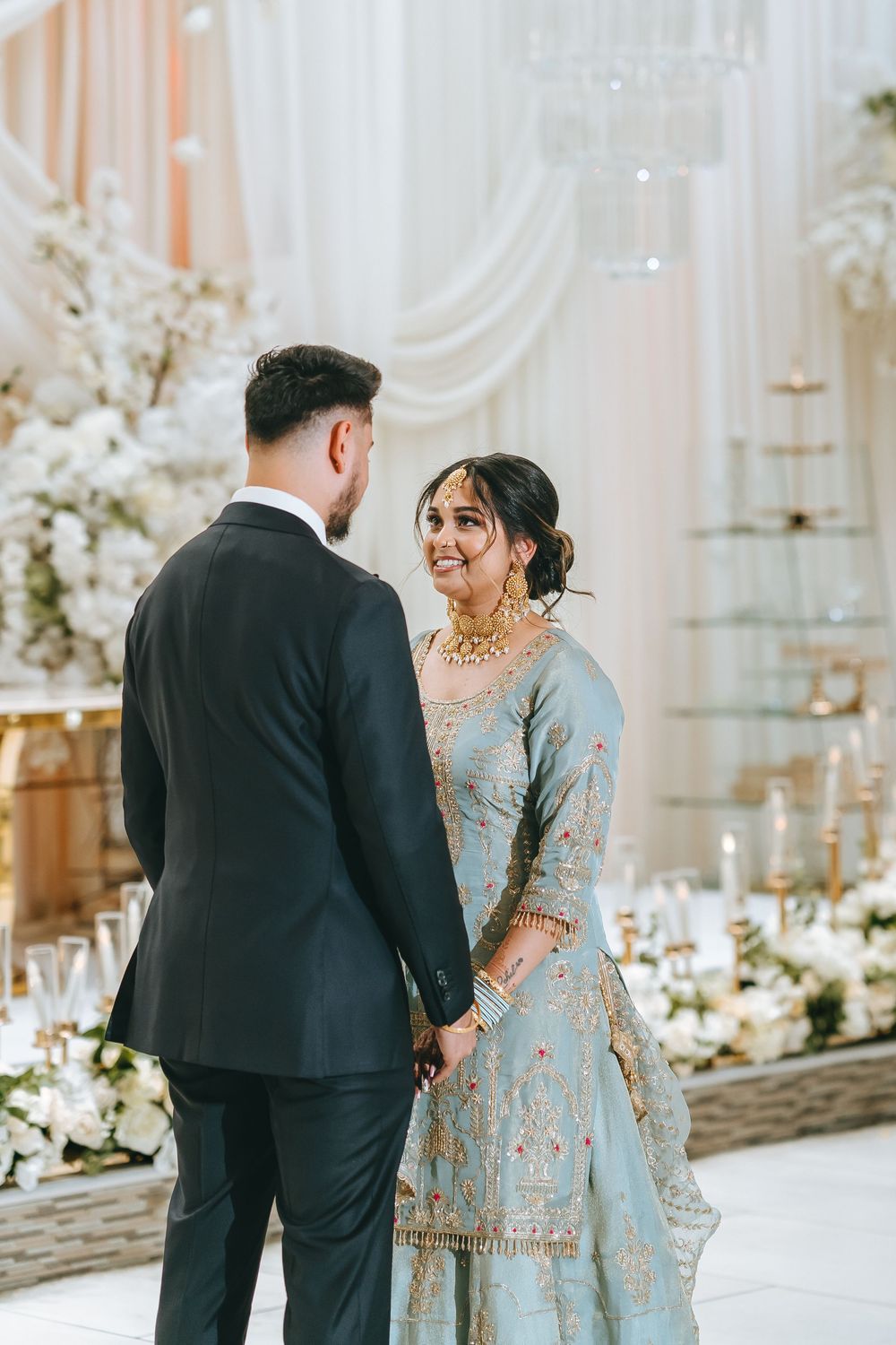 Candid wedding photos showing a couple sharing joyful moments in a beautifully decorated white venue.
