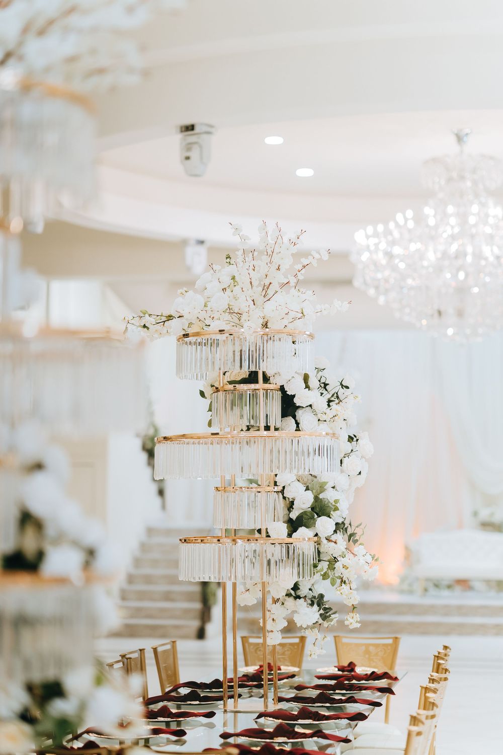 Elegant wedding venue featuring white draping, floral arrangements and a couple in formal attire.