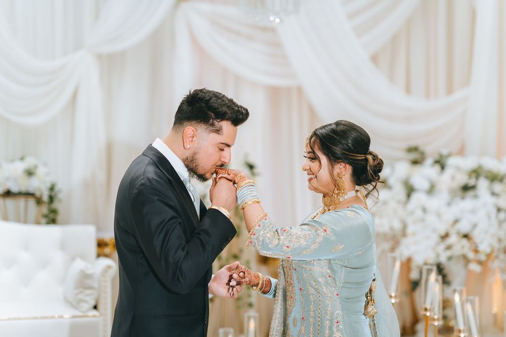 An intimate moment between newlyweds during their wedding ceremony with white drapes and floral decor.