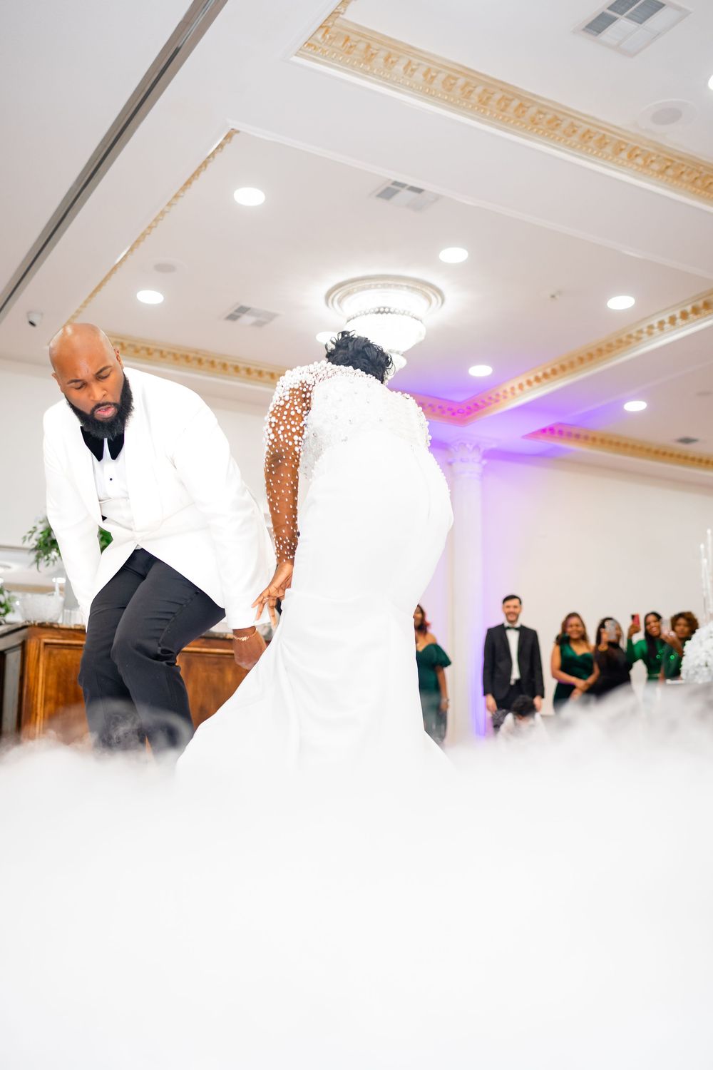 A wedding couple performs a dance lift move on the dance floor during their reception celebration.