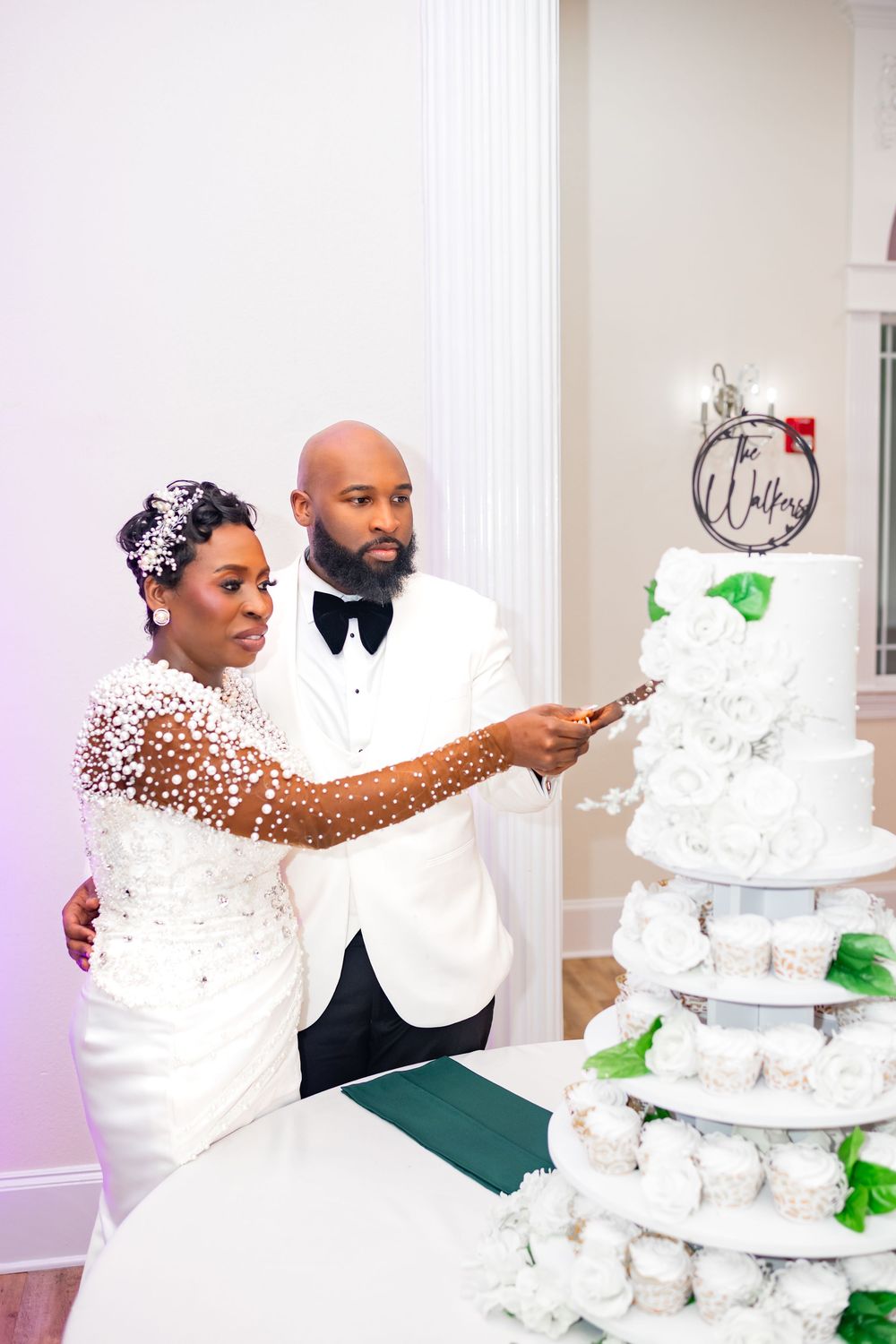 A couple playfully cuts their elegant white wedding cake together at their reception celebration.