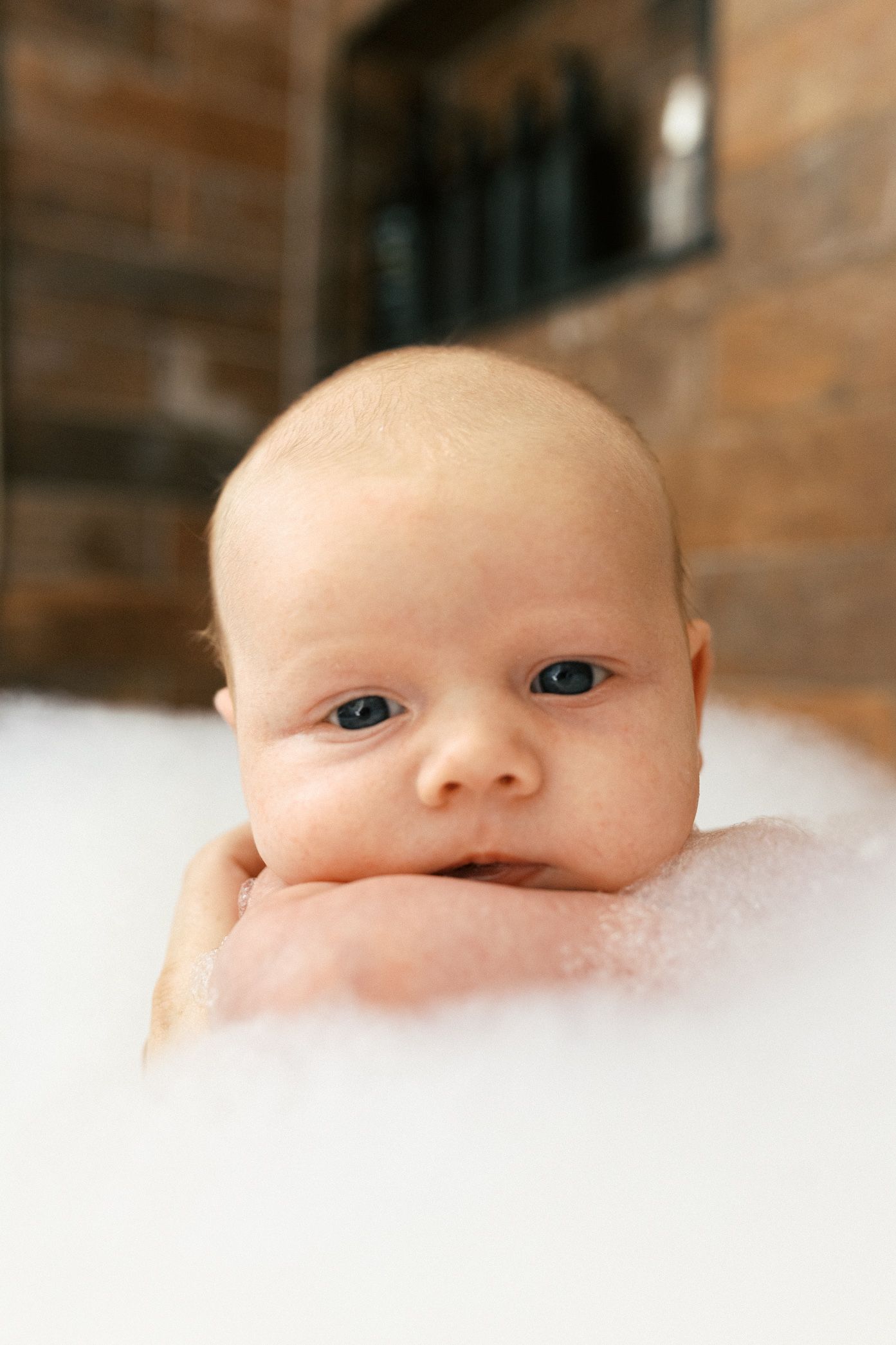 Close-up view of an infant's face peeking out from soft white bedding.