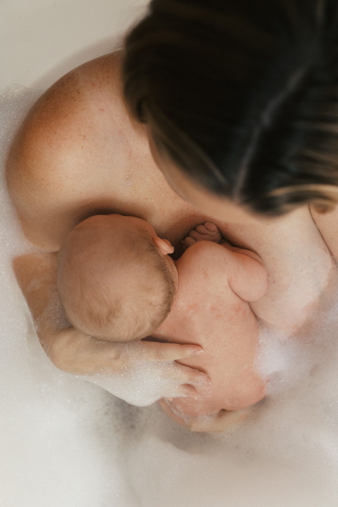 Intimate black and white portrait showing a nurturing moment between caregiver and baby.