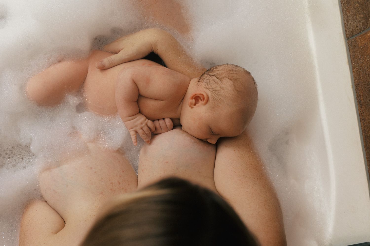 A baby relaxing in a bathtub filled with soapy bubbles during bath time.