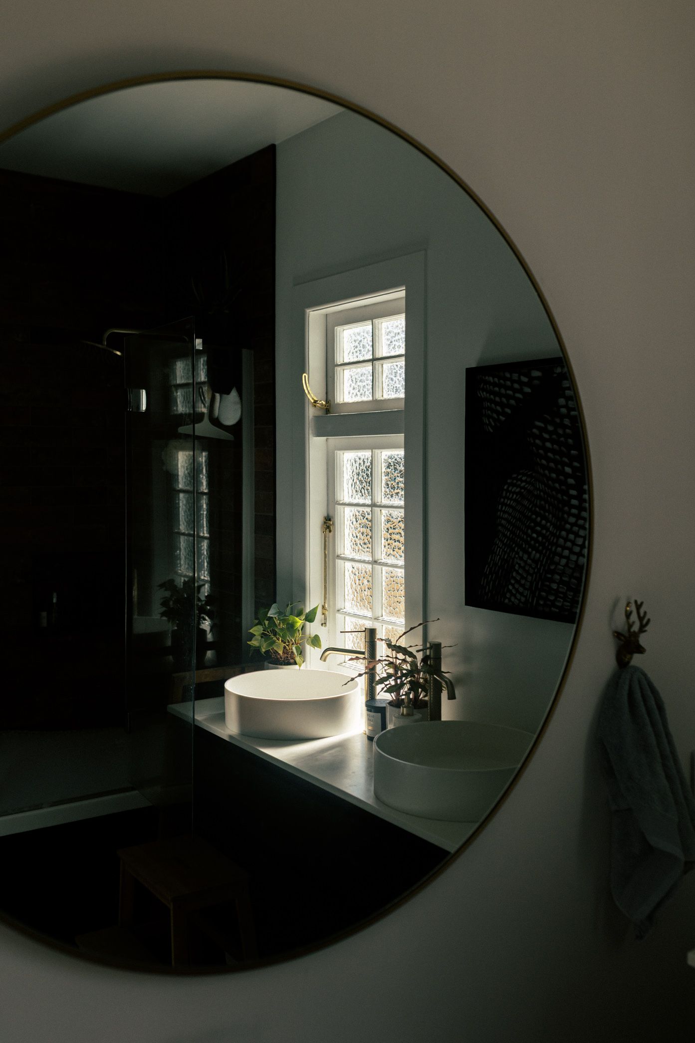 Sunlight streams through a window in a dark room with a large circular mirror creating dramatic shadows and reflections.