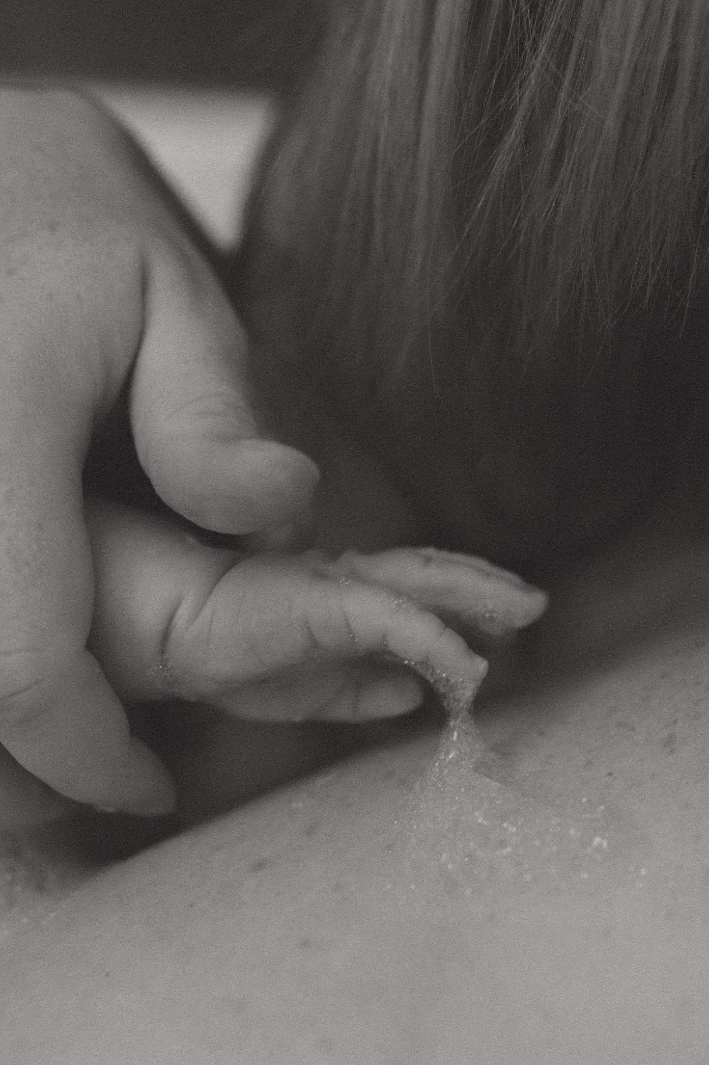 Close-up sequence of hands kneading and working with sticky dough or clay material in black and white.