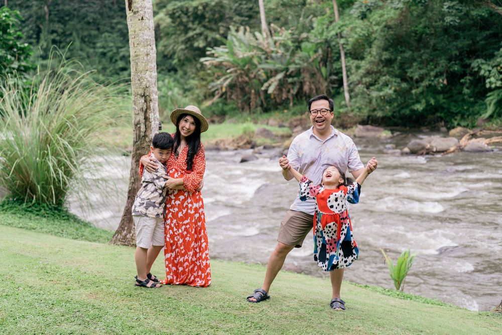 A group enjoys a scenic outdoor photoshoot along a rushing river surrounded by lush greenery.