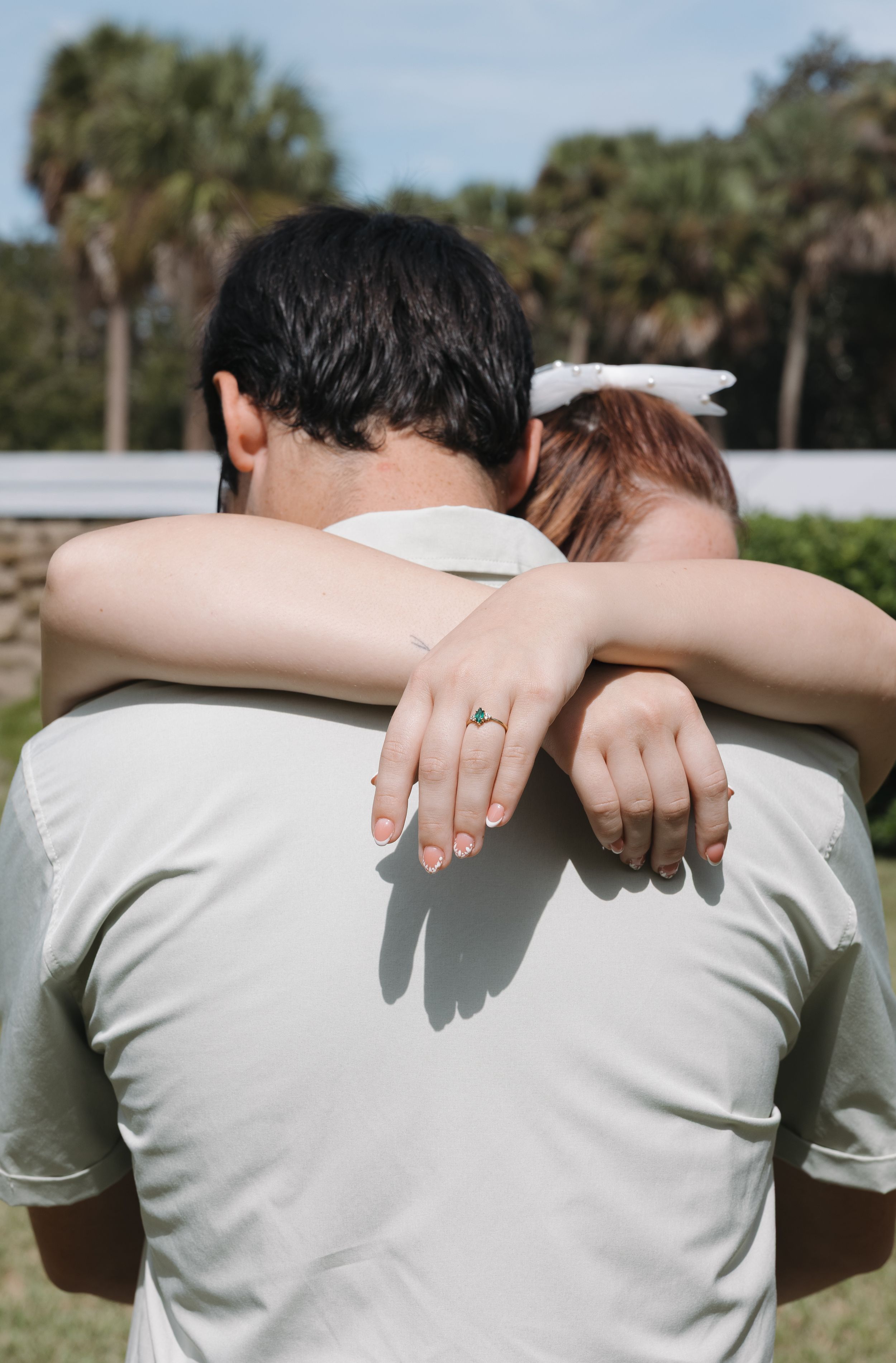 Hands rest lovingly on shoulders in an outdoor garden setting.