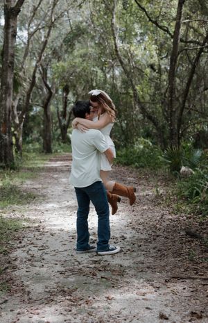 A playful dance pose on a wooded path with brown boots.