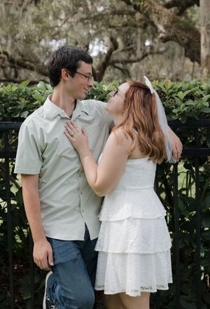 A sweet moment shared between a couple by a black iron fence in a garden setting.