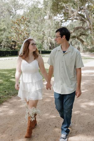A couple walks hand in hand along a scenic outdoor path.
