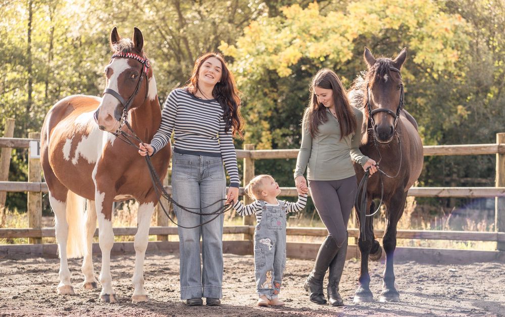 A group of people and horses gather outdoors during a sunny day for equine activities and training.