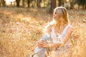 A person in a white dress walks through a golden field at sunset creating a dreamy summer atmosphere.