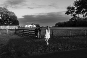 A panoramic view of a rural farmhouse with white fencing stretches across rolling hills.