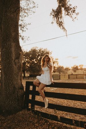 White fence in a pastoral setting at golden hour with oak trees and Spanish moss creating a dreamy scene.