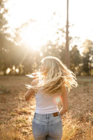 Hair flowing in motion against golden sunset light filtering through trees in a forest setting.