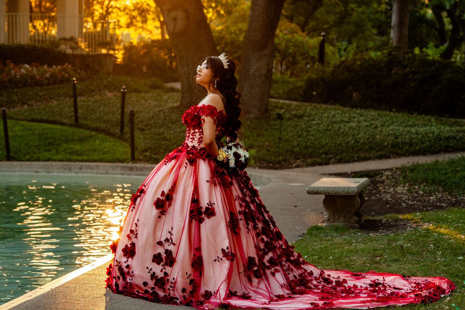 Dramatic sunset photo of a red ball gown dress with a flowing train in an outdoor setting.