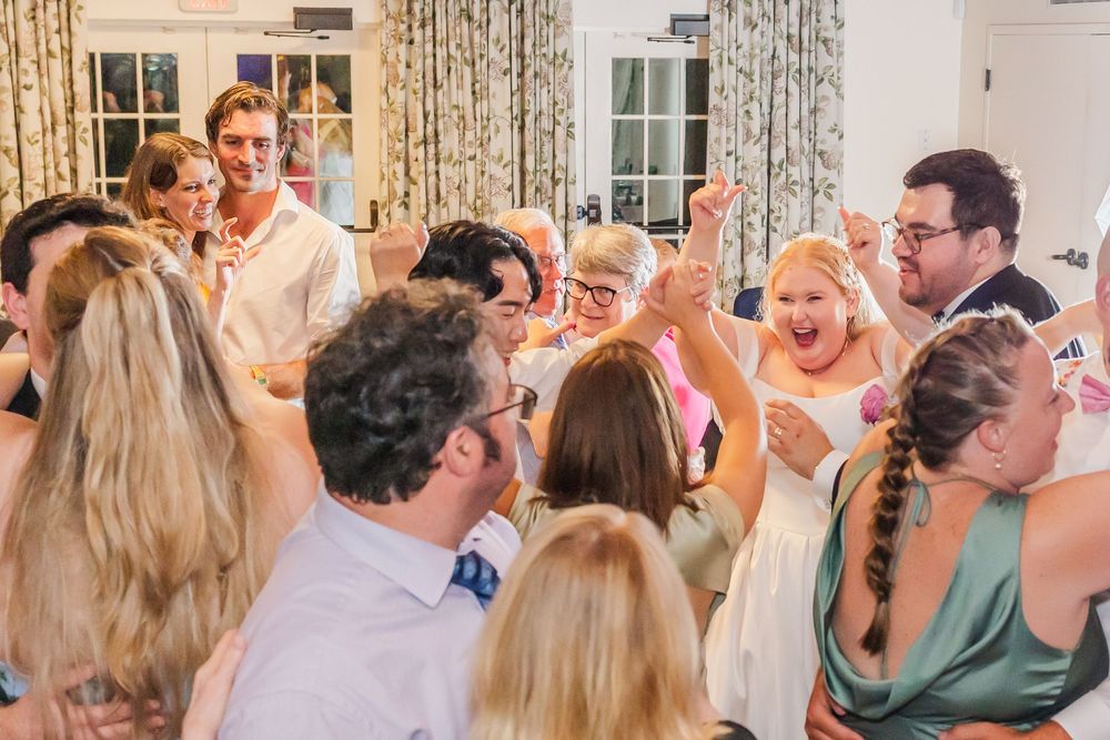 Wedding reception guests dance and celebrate together on a crowded dance floor during a joyous celebration.