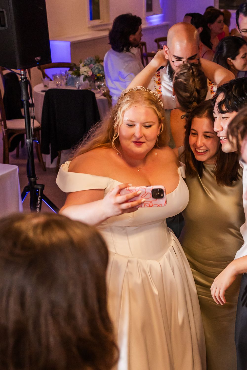 Wedding guests share emotional hugs and embraces on the dance floor during a reception celebration.