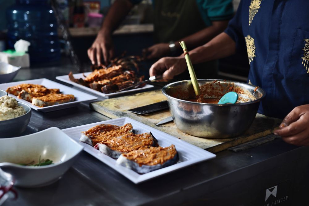 Multiple plates of food being served in a dimly lit restaurant setting.