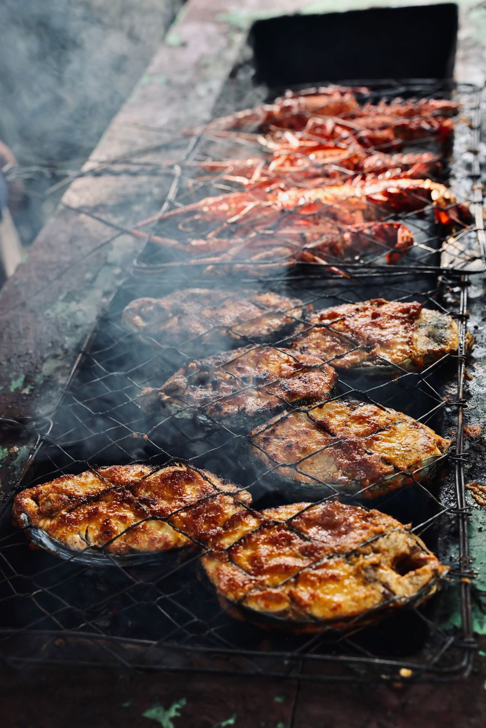 Grilled meat sizzling on a barbecue grill with rising smoke.