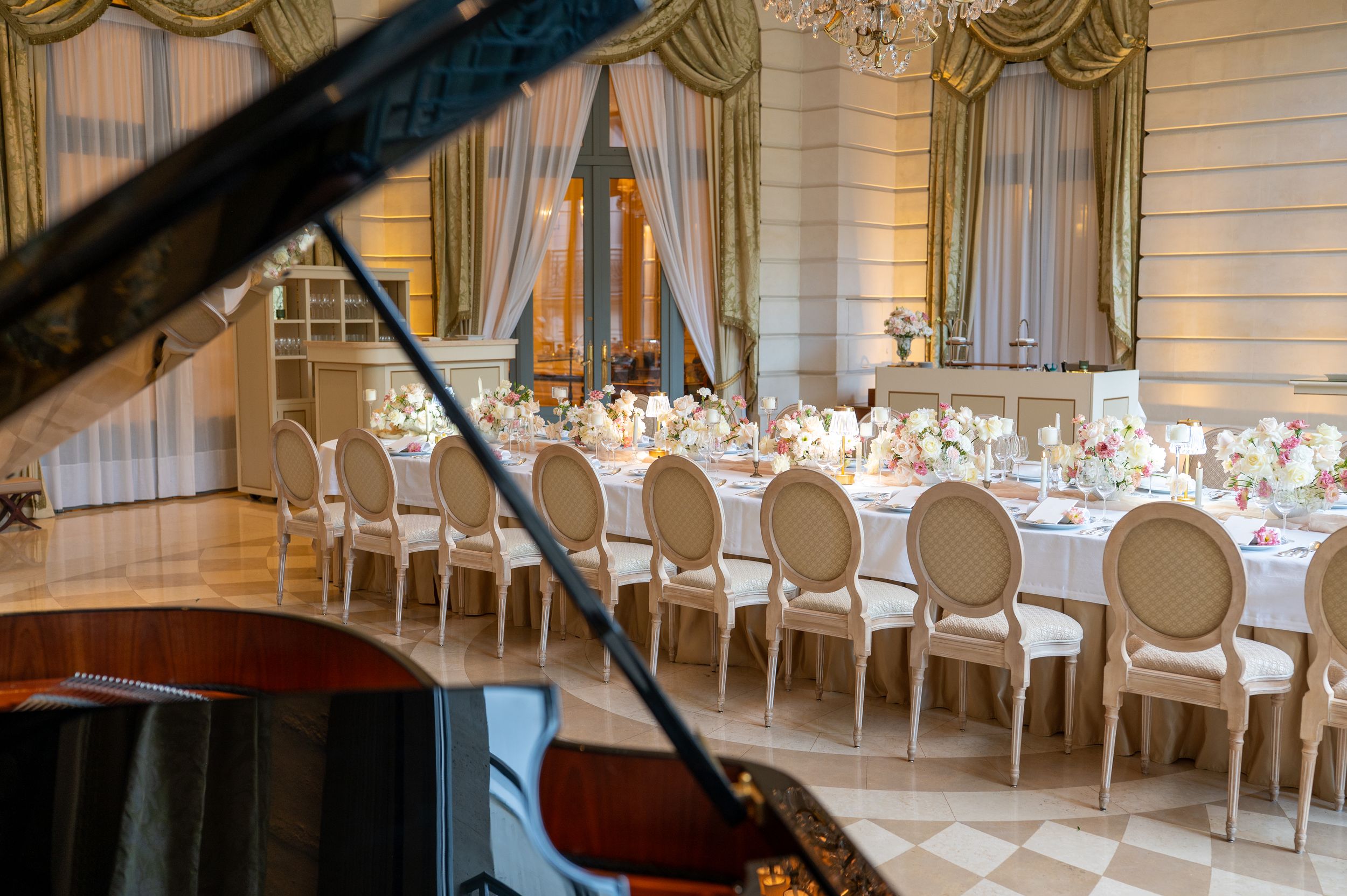 Lieu de réception de mariage élégant avec lustres en cristal, chaises blanches et décors de table formels dans une salle de bal luxueuse.