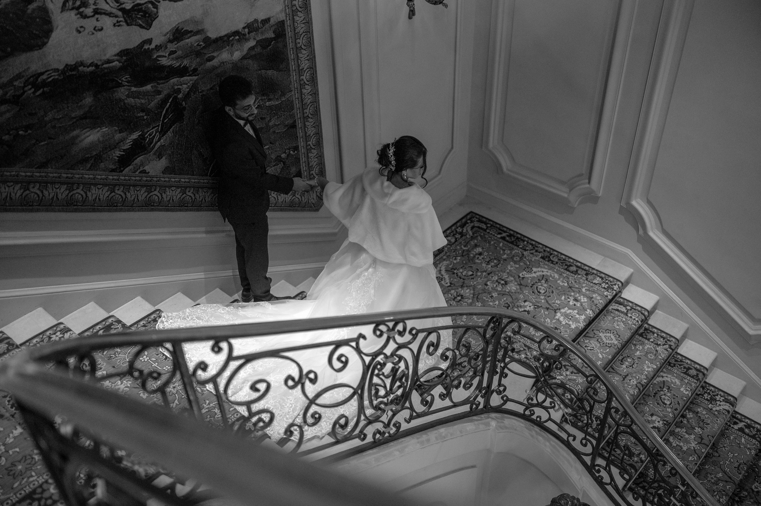 Photo en noir et blanc d'une rampe d'escalier en fer forgé ornée avec des détails architecturaux classiques.