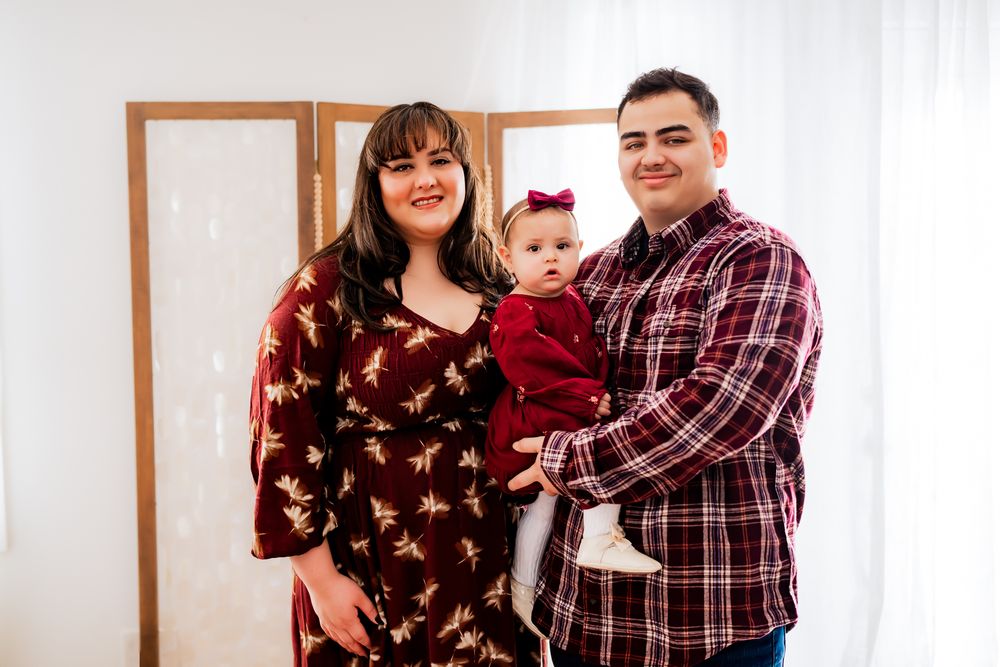 A group poses together for a casual photo session in a bright interior space wearing coordinated burgundy outfits.