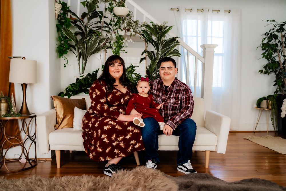 Family photo session in bright room with houseplants showing tender moments between parent and child.