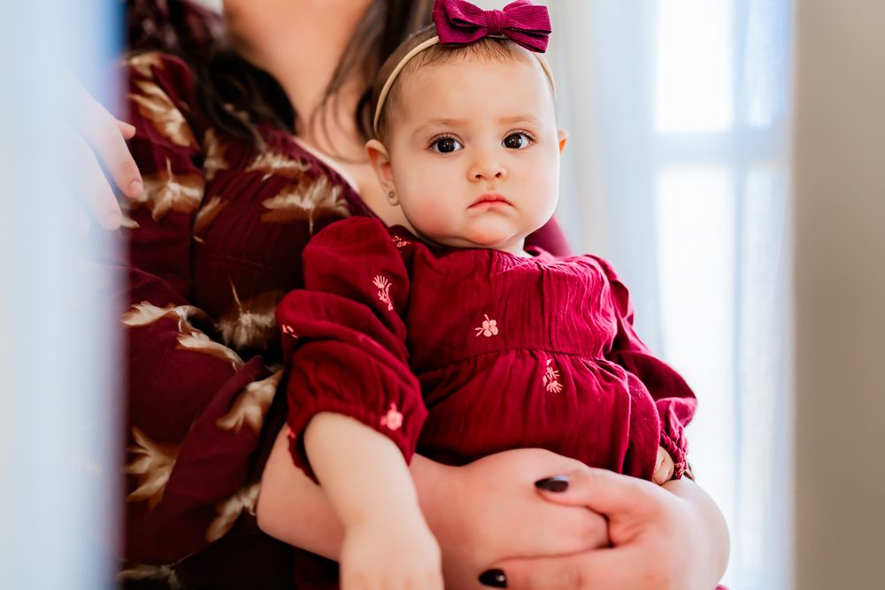 A small child in red clothing sits with family members in a bright, minimalist interior space.