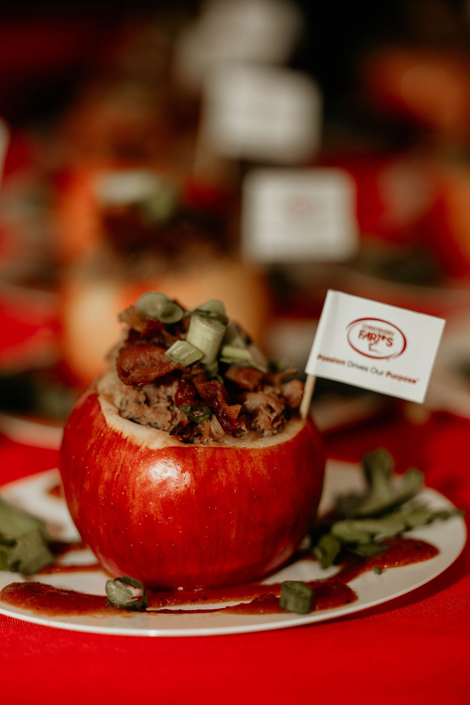 A stuffed red apple dish served on a white plate against a red tablecloth creates an elegant presentation.