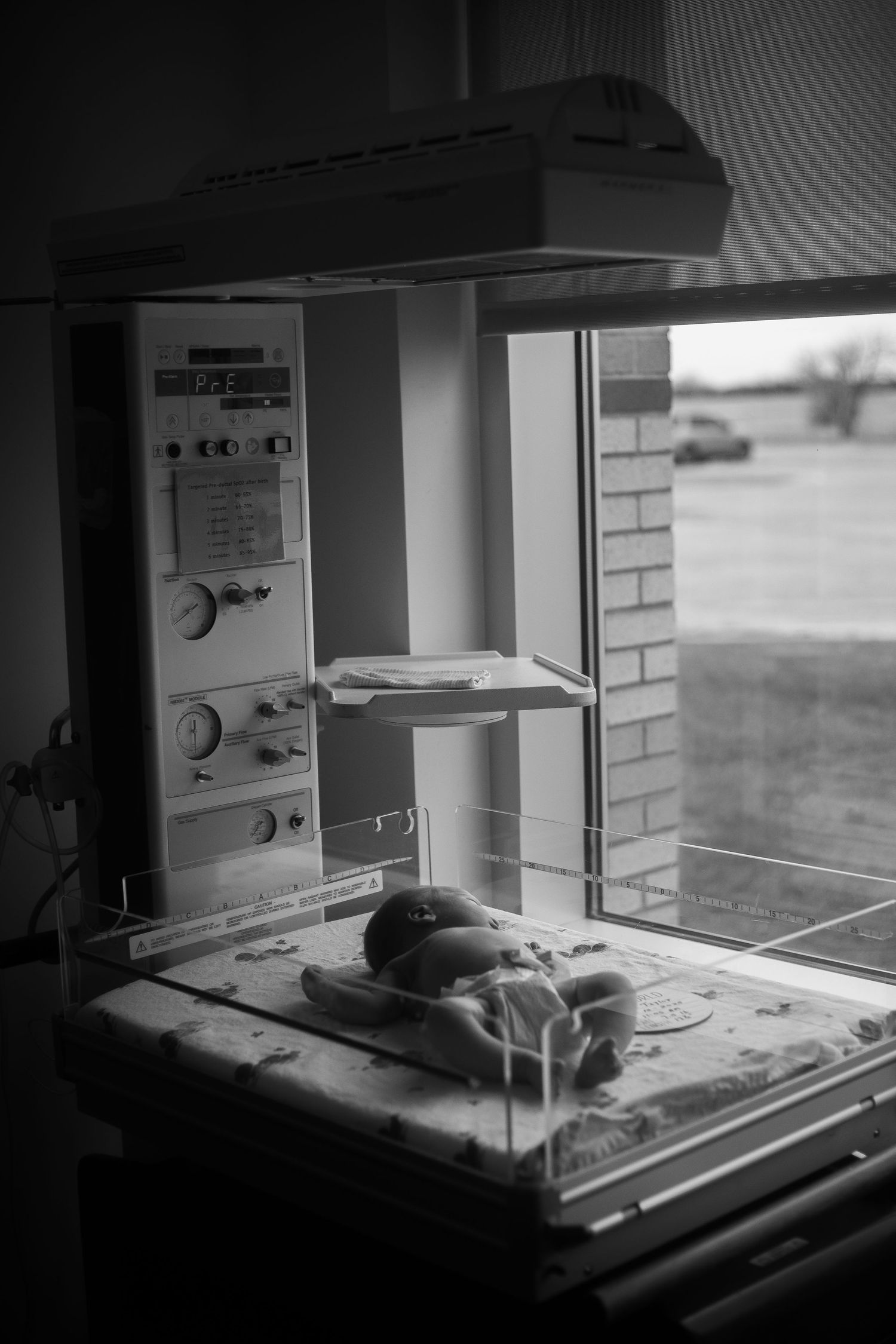 Black and white photo sequence showing a hospital incubator or warming bed for newborns in a medical setting.