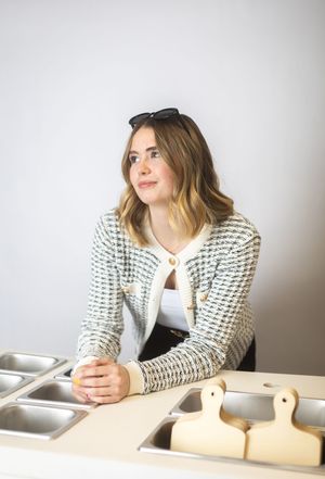 Person wearing a black and white patterned sweater sits at a desk with a phone and laptop.