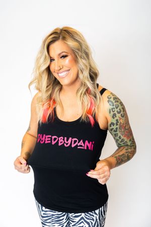 Person in black tank top with tattoo sleeve poses against white background in four different casual poses.