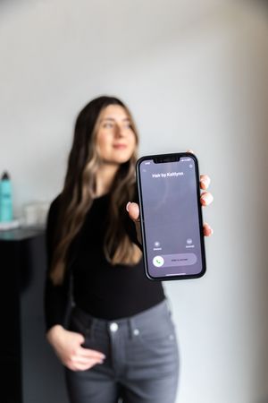 Person in dark clothing shows smartphone screen in sequence of blurred motion photos against gray background.