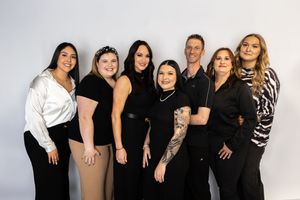 A group poses together wearing coordinated black and white outfits against a light background for a professional photo.