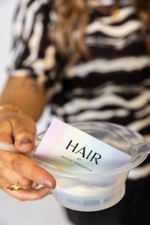 Close-up sequence showing hands opening a translucent plastic container labeled 'HAIR' against a zebra print background.