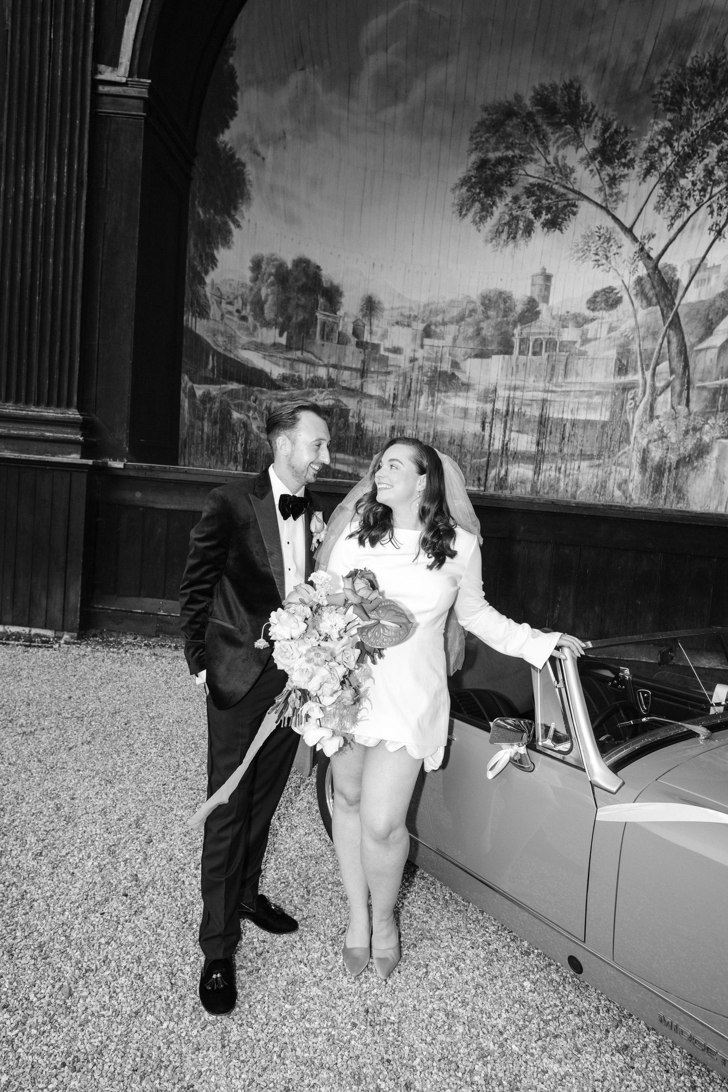 A black and white photo sequence shows a couple in formal attire playfully posing by a car. Taken by modern editorial wedding photographer.