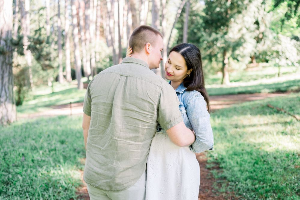 A couple walking together on a forest path surrounded by tall pine trees.