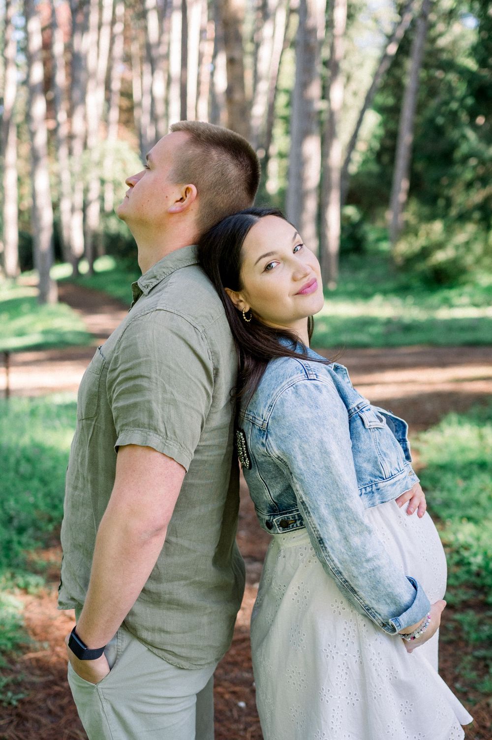A romantic moment captured in a pine forest with sunlight filtering through the trees.