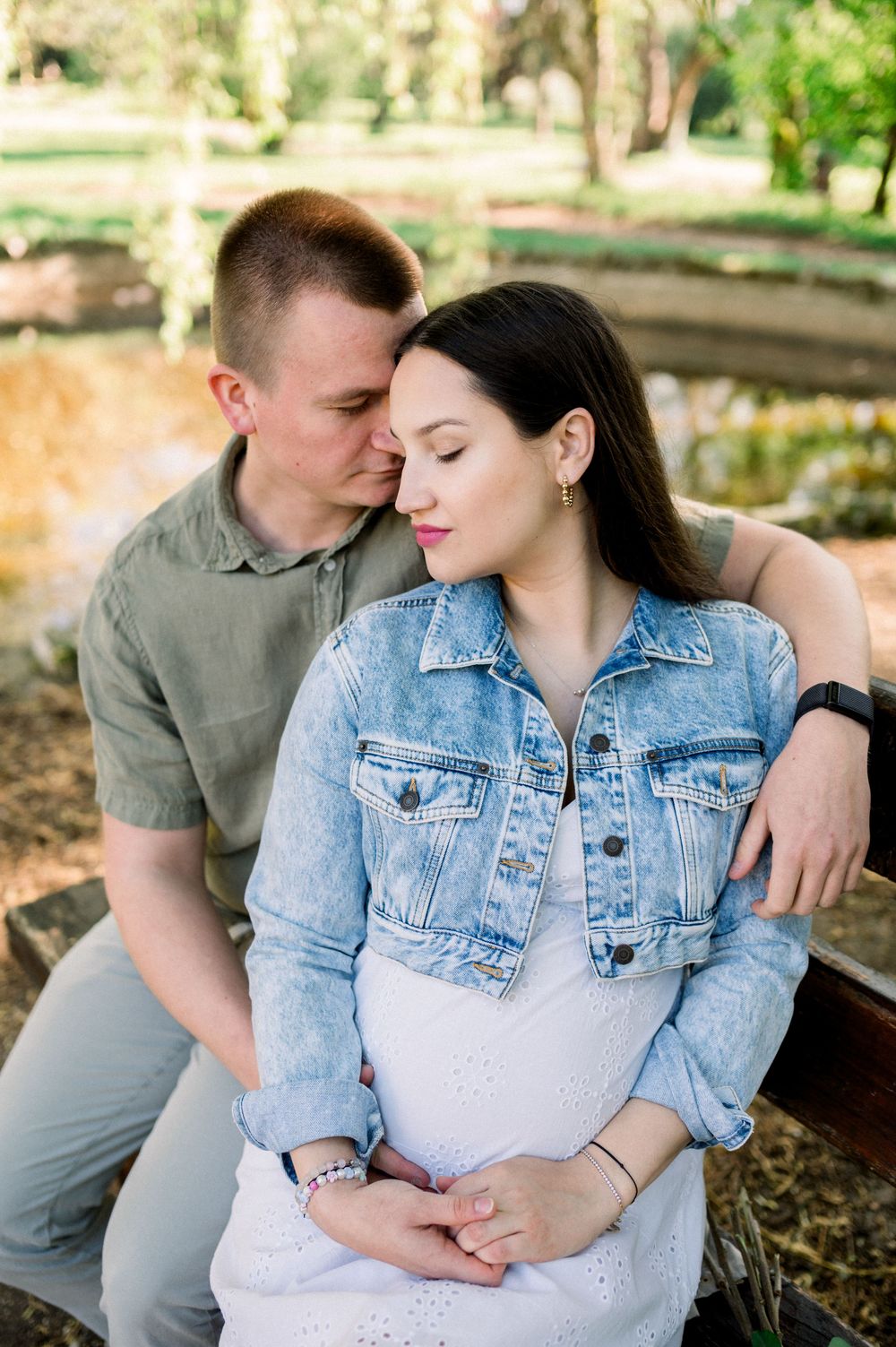 Couple in denim jacket and olive shirt share tender moments on a sunny afternoon.